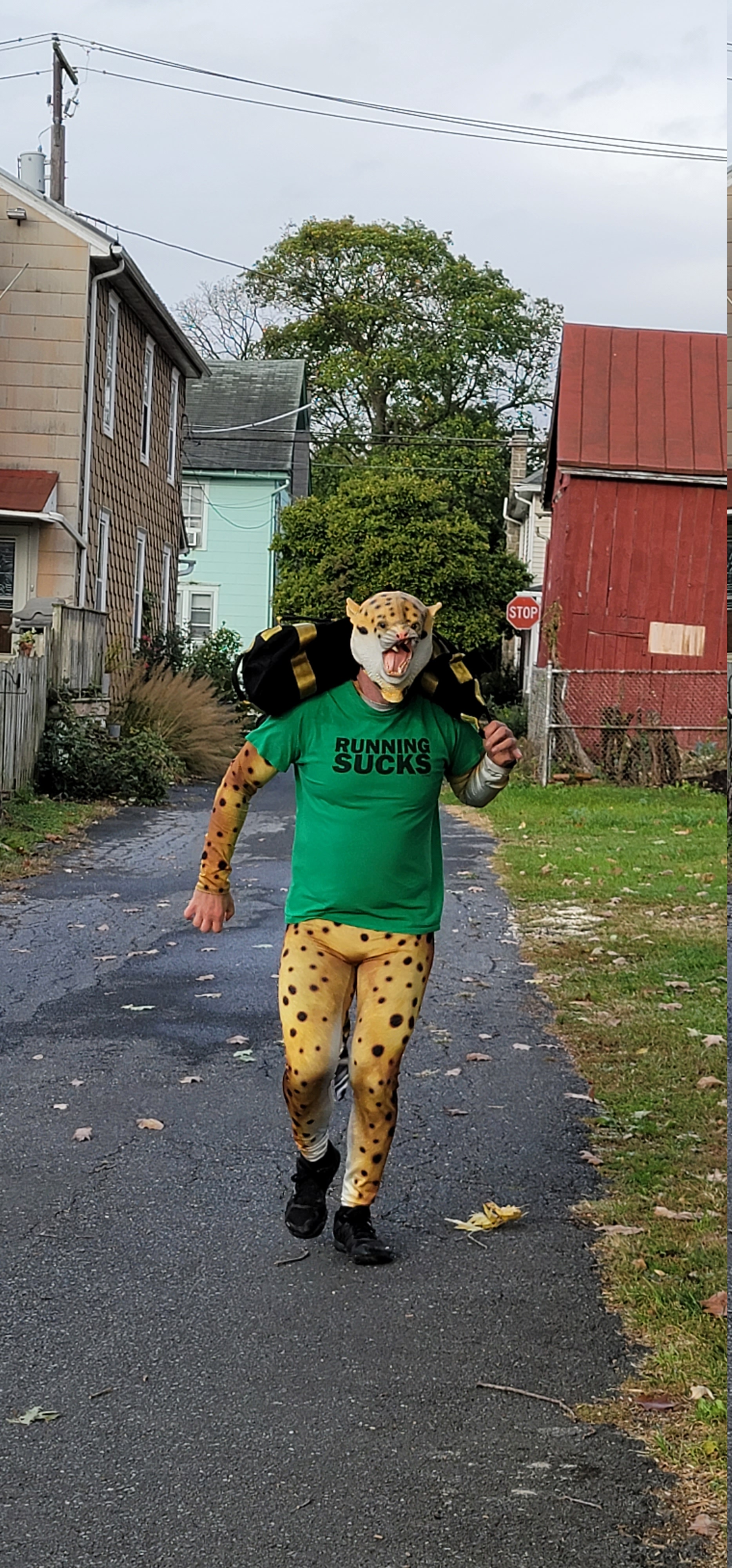 This is a picture of me running with a sandbag on my shoulder. I have my cheetah costume on with a cheetah mask. My tshirt that I am wearing over it says 